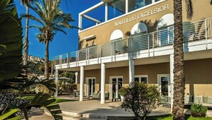 A hotel with a name sign 'NAUTILUS EXCELSIOR' on the facade, featuring a modern architectural style with a balcony and a covered entrance area. - Hotel Nautilus Excelsior - Adults Only (Cagliari)