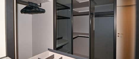 A walk-in closet with open shelving, a hanging rod, and a door.