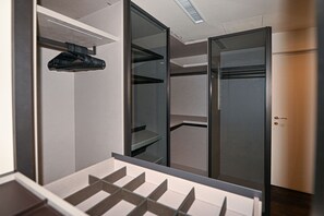 Ein begehbarer Kleiderschrank mit offenen Regalen, einer Kleiderstange und einer Tür.