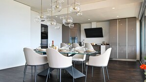 Uma sala de jantar moderna com mesa de vidro, cadeiras brancas e uma luminária esférica singular.