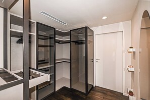Un interior moderno con un separador de vidrio, una puerta blanca y un estante con adornos decorativos.