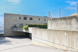 A concrete building with a flat roof, a small garden area with a hedge, and a clear sky. - Luxury Corba Lake View Apartment With Terrace (Canobbio)