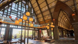 A spacious interior with high ceilings, large windows, and hanging spherical light fixtures. - Ko Olina | Disney Family Adventure | Lagoon + Pool | 2BR (Kapolei)