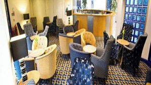 A hotel lobby with seating areas, a reception desk, and a patterned floor.