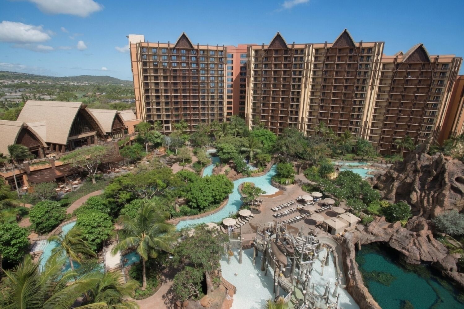 A resort with multiple swimming pools, a waterfall, and lush greenery.