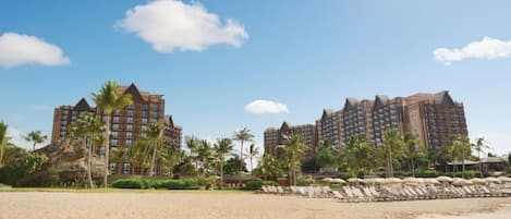 A beachfront hotel with multiple high-rise buildings, palm trees, and a sandy beach.
