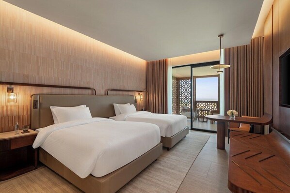 A hotel room with two beds, a desk, a TV, and a balcony with a view.