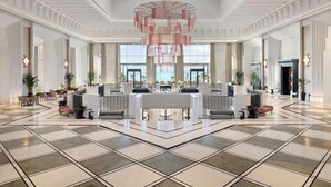Un hall d’entrée spacieux avec un comptoir d’accueil central, de grandes fenêtres et un lustre décoratif.