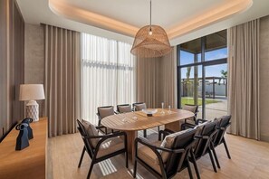 A modern dining area with a round table, chairs, and a hanging light fixture.