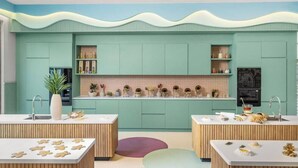 Une cuisine moderne avec des meubles de couleur turquoise, un îlot central et un pare-feu décoratif.