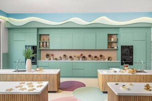 Eine moderne Küche mit türkis-blauen Schränken, einer zentralen Kochinsel und einer dekorativen Rückwand.