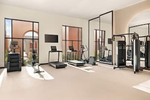 A modern gym with various exercise equipment, large windows, and a minimalist design.