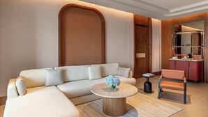 A modern living room with a sofa, a coffee table, and a chair. There is a kitchen area visible in the background.