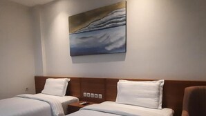 A hotel room with two beds, a painting on the wall, and a chair. - Gemma Hotel Balige (Balige)