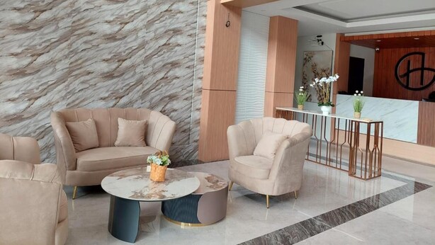 A modern lobby with a marble wall, a reception desk, and a seating area with a coffee table. - Gemma Hotel Balige (Balige)