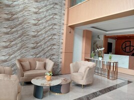 Um lobby moderno com parede de mármore, balcão de recepção e área de estar com mesa de centro.