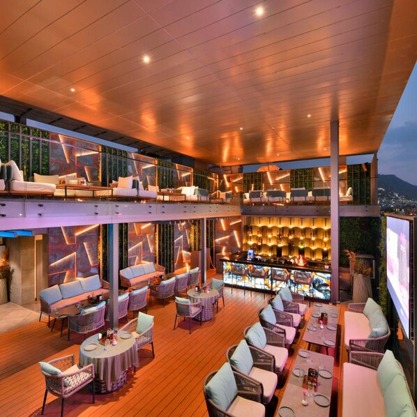 A rooftop bar with multiple seating areas, a bar counter, and a view of the cityscape. - Clarks Collection Grand Sapphire Ajmer (Ajmer)