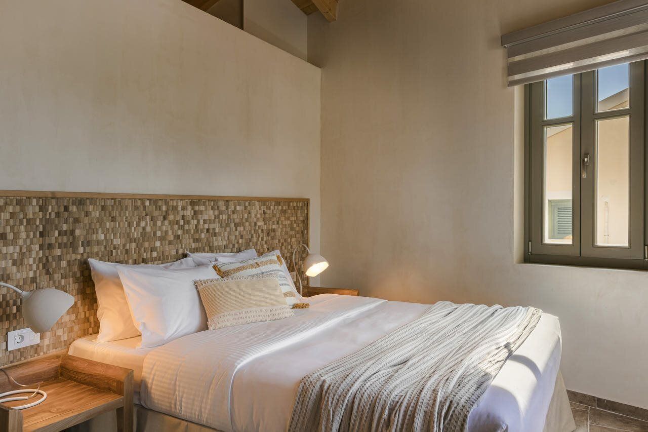 A bedroom with a bed, bedside tables, a lamp, and a window.