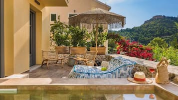 An outdoor pool area with lounge chairs, a table, and a decorative umbrella.