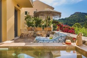 An outdoor pool area with lounge chairs, a table, and a decorative umbrella.