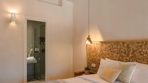 A hotel room with a bed, a nightstand, a wall-mounted lamp, and a shower area. - Chromata Assos Villas Kefalonia (Kefalonia)