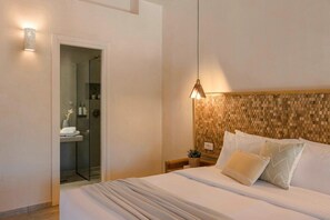 Habitación de hotel con cama, mesita de noche, lámpara de pared y zona de ducha.