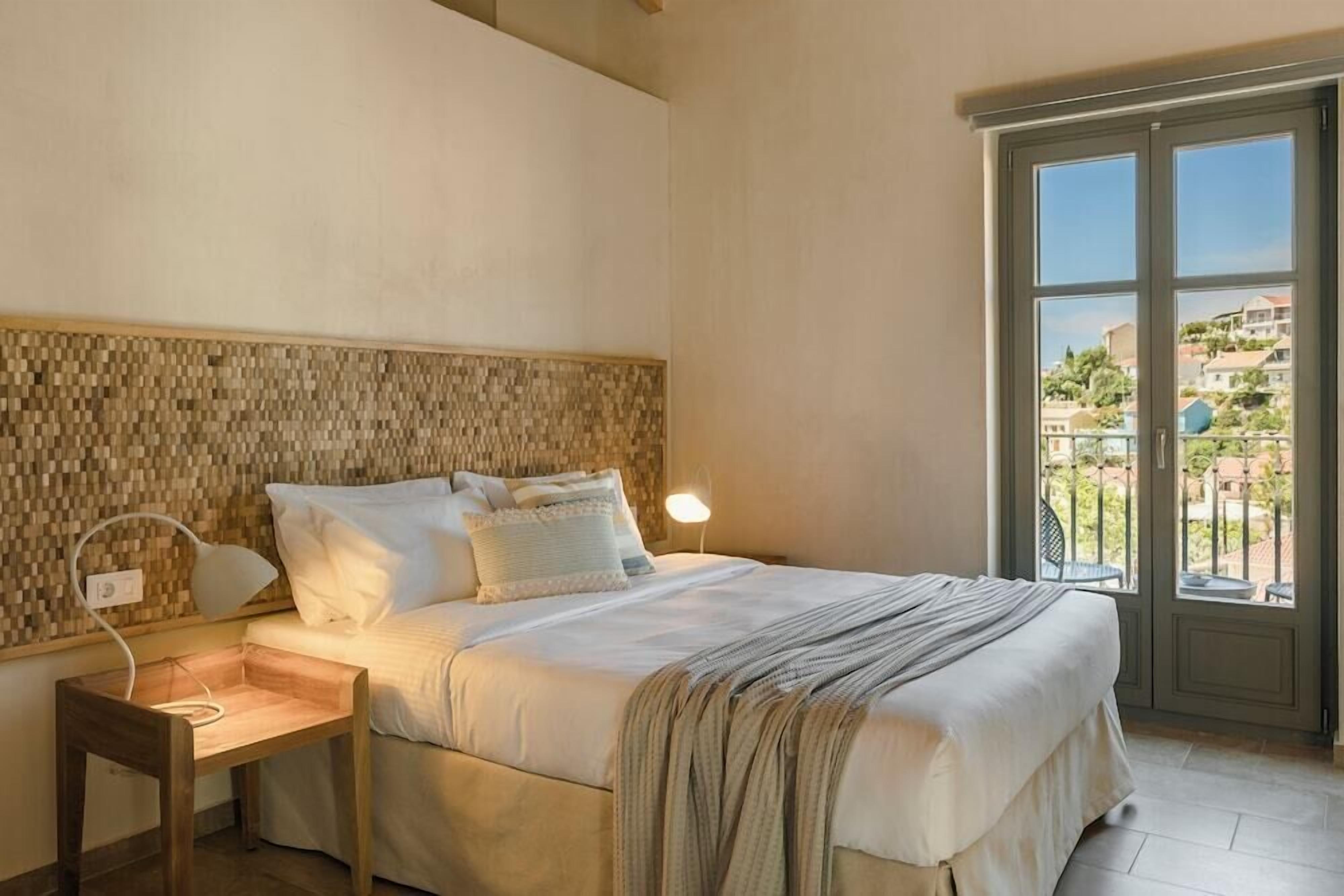 Un dormitorio con cama, mesita de noche, lámpara y vistas a través de una puerta.