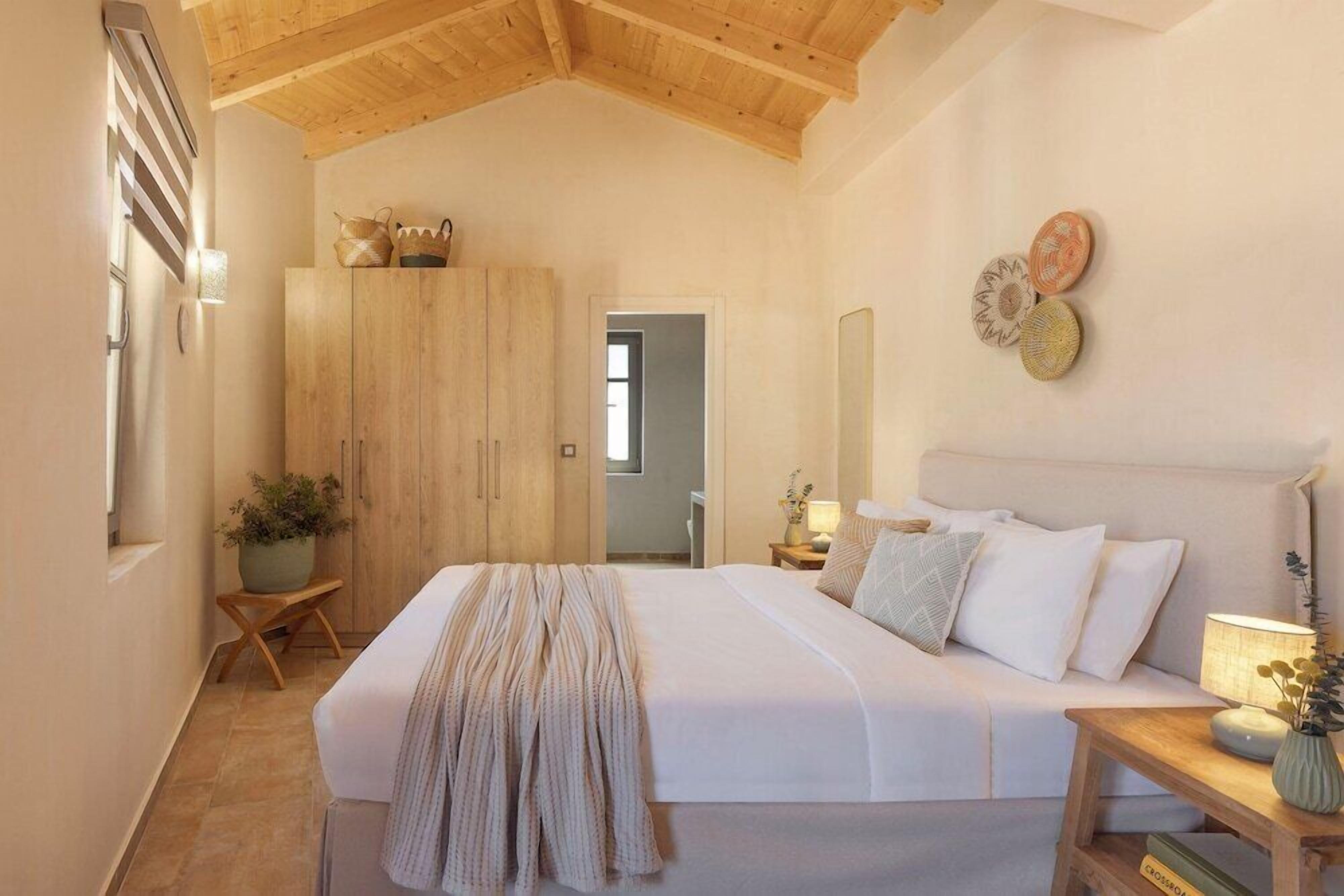 A bedroom with a large bed, wooden wardrobe, and a bedside table with a lamp.