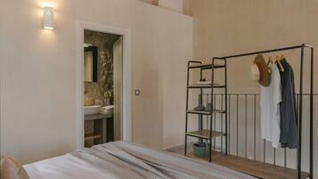 A bedroom with a bed, a wardrobe, a mirror, and a wall-mounted light fixture.