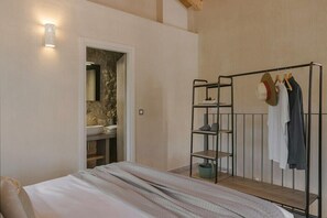 Un dormitorio con cama, armario, espejo y lámpara de pared.