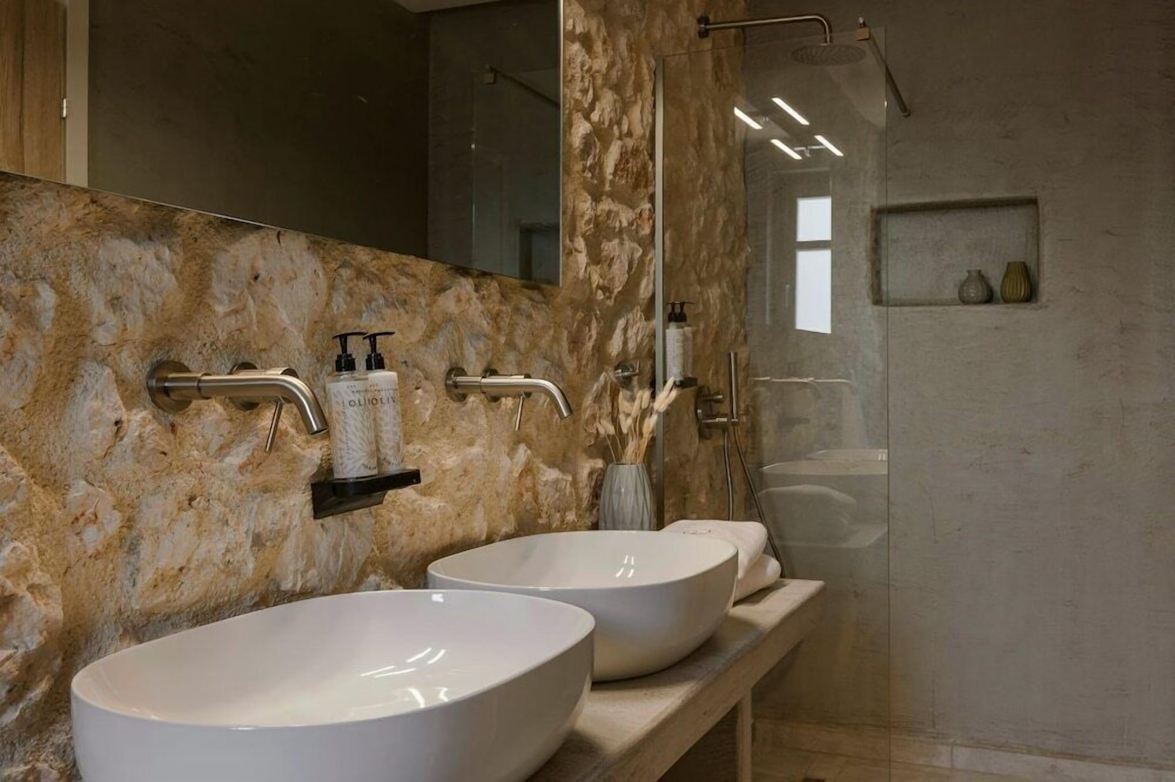 Un baño con dos lavamanos blancos, un espejo y una zona de ducha.