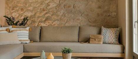 A cozy living room with a stone wall, a sofa, a coffee table, and a hanging light fixture.