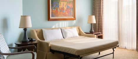 A hotel room with a bed, a chair, two bedside tables, a lamp, a painting, and a window with curtains.
