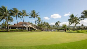 A golf course with a clubhouse, palm trees, and a clear sky. - Ko Olina | Disney Family Adventure | Lagoon + Pool | 3BR Sleeps 12 (Kapolei)