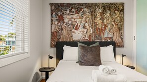 A hotel room with a large tapestry, a bed with white linens, two bedside tables, and a view of the outside through the window. - The Leafy Outlook Family Stay in Randwick (Randwick)