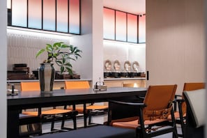 Un espace repas moderne avec une longue table, des chaises et une plante en pot.