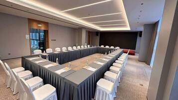 A conference room with a long table, chairs, and a projector screen.