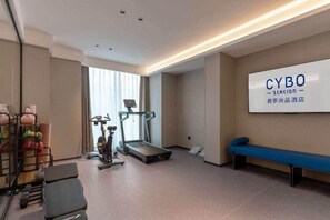 Habitación de hotel con una cinta de correr, equipo de ejercicio, una banca y un gran letrero CYBO Station.