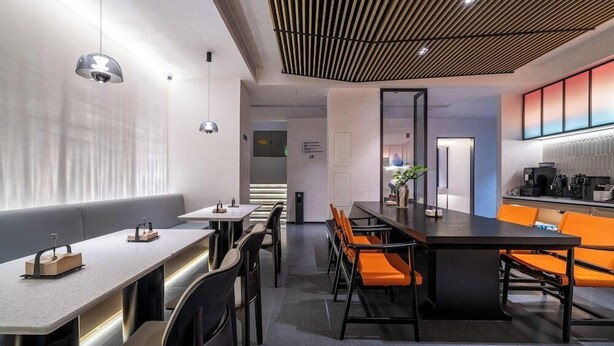 Een modern interieur met een lange gemeenschappelijke tafel, individuele zitplaatsen en een keukenhoek.