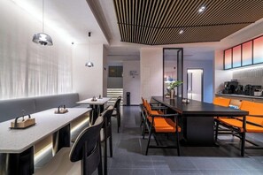A modern interior with a long communal table, individual seating, and a kitchen area. - Chengdu Tianfu Square Chunxi Road Pagoda Premium Hotel (Chengdu)