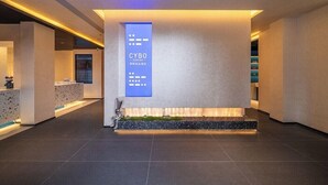 Een moderne receptiebalie met een CYBO sign, een receptie en een zithoek met een kleine plant.