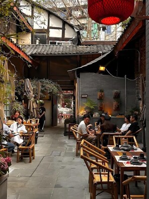 Un área de comedor al aire libre con mobiliario de bambú y diversas plantas.