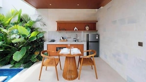 Una cocina moderna con armarios de madera, un refrigerador de acero inoxidable y un comedor con mesa y sillas de madera.