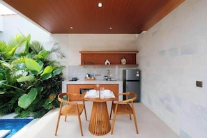 A modern kitchen with wooden cabinets, a stainless steel refrigerator, and a dining area with a wooden table and chairs.