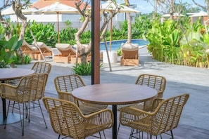 A poolside area with wicker furniture and umbrellas.