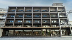 A multi-story hotel with a modern design, featuring balconies on each floor, a ground-level entrance with seating, and a clear sky above. - Surestay Plus by Best Western Ramkhamhaeng Airport Rail Link Bangkok (Bangkok)