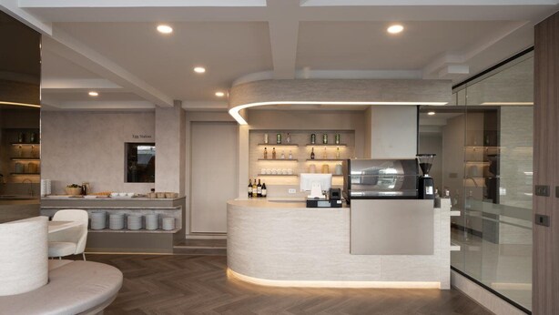 Una cocina moderna con una isla curva, electrodomésticos integrados y un separador de vidrio.
