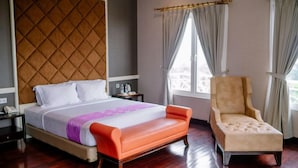 A hotel room with a bed, a chair, a nightstand, and a window with curtains. - Beth Kasegaran Theresia (Megamendung)