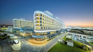 A modern hotel with a curved facade, multiple floors, and a well-lit entrance. - Hilton Garden Inn Guangzhou Baiyun Airport (Guangzhou)