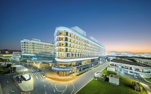 A modern hotel with a curved facade, multiple floors, and a well-lit entrance. - Hilton Garden Inn Guangzhou Baiyun Airport (Guangzhou)